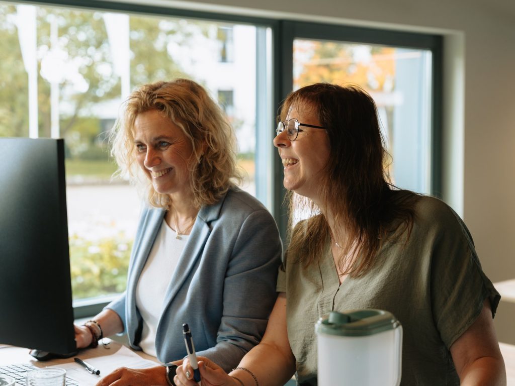 Twee collega’s van Keizer International werken samen achter een beeldscherm